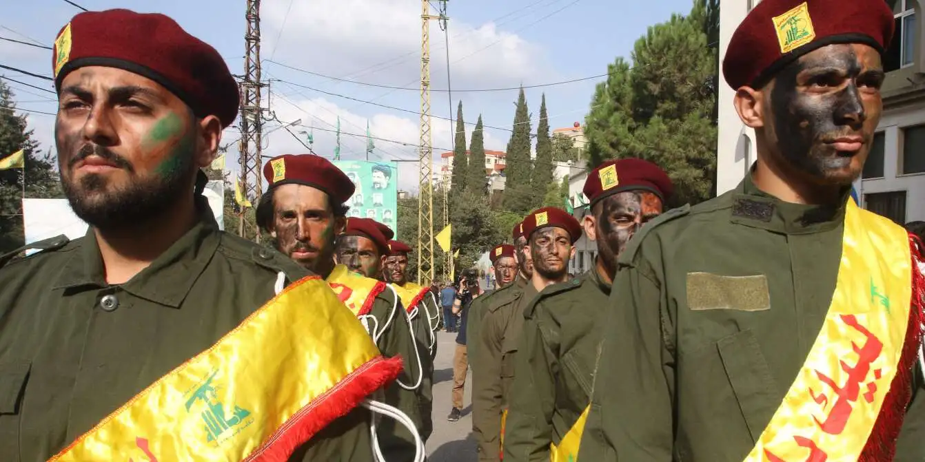 Hezbollah fighters standing in formation, armed and wearing military uniforms.