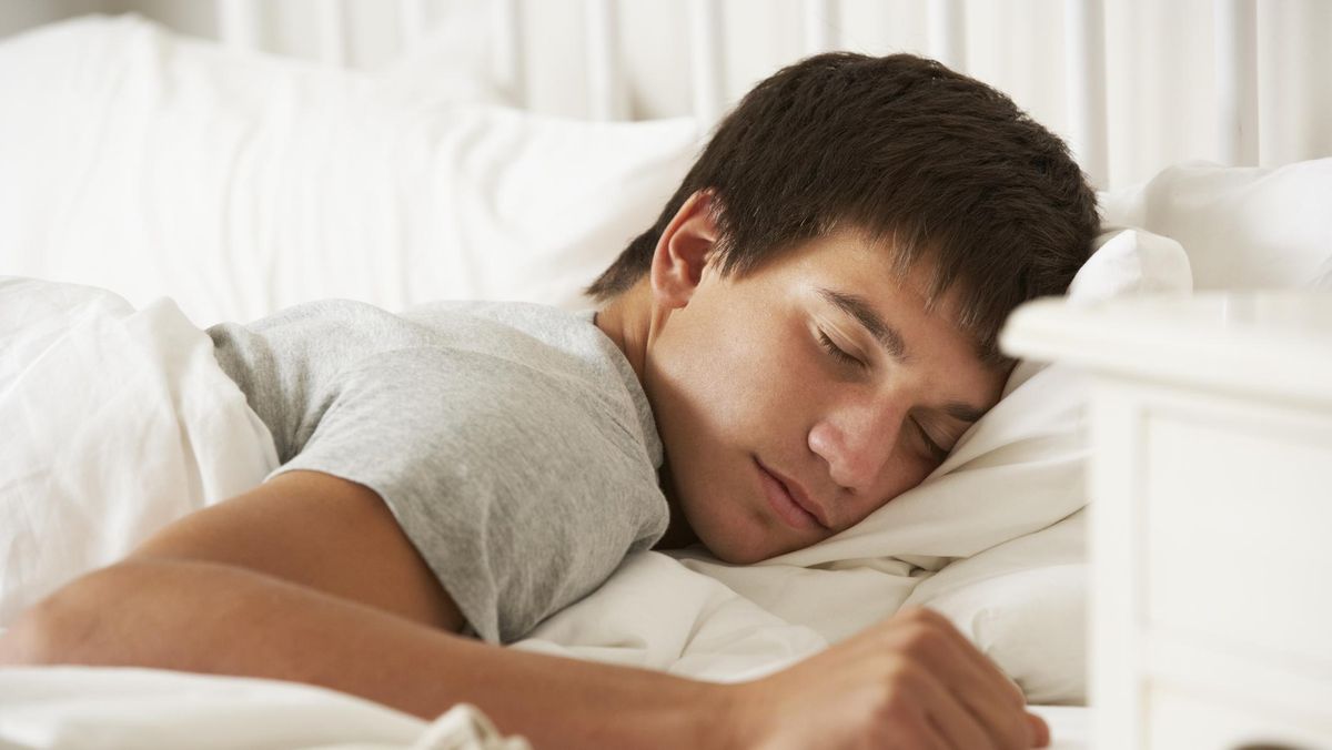 A person sleeping peacefully in bed, surrounded by various sleep-tracking devices