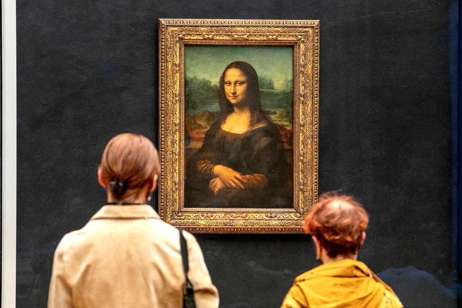 Visitors admiring the Mona Lisa at the Louvre, highlighting the painting's cultural and historical significance.