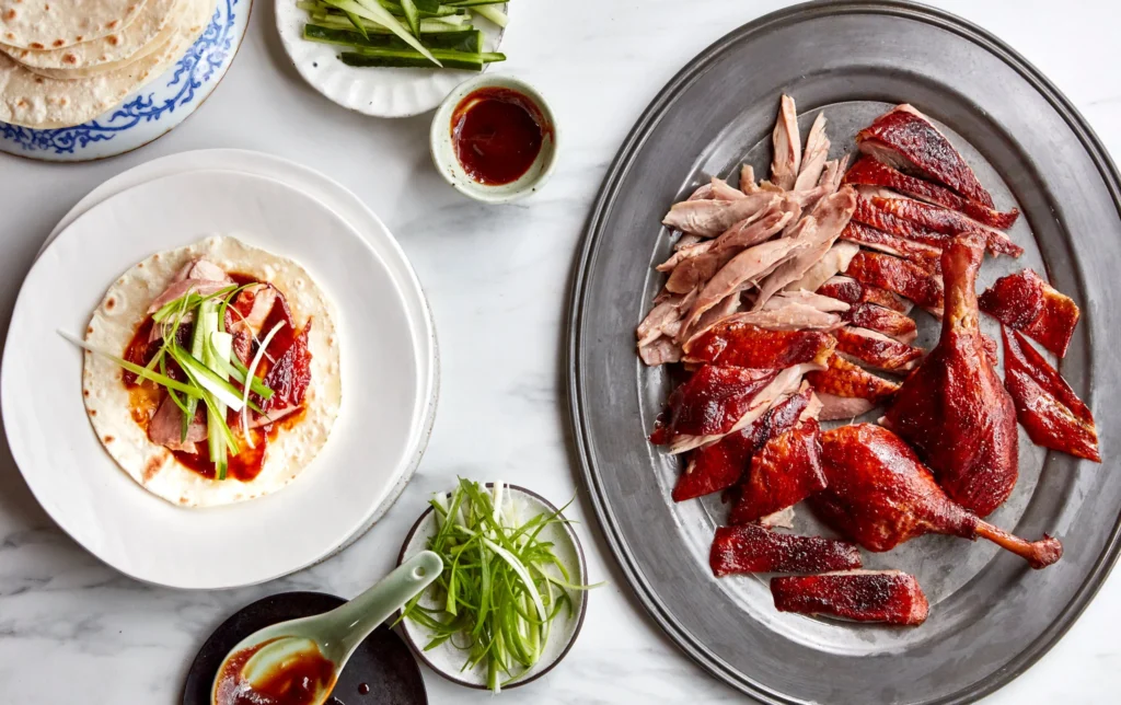 A close-up of Peking Duck pancakes filled with tender duck slices, cucumber, and spring onions