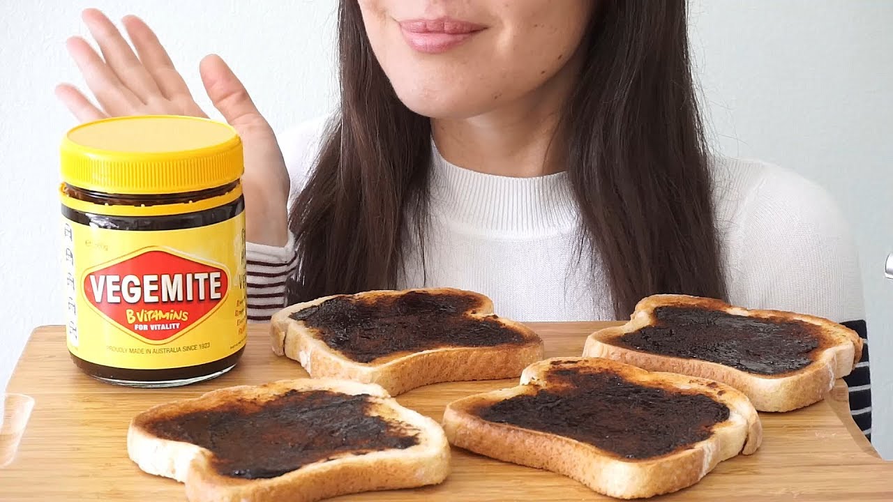 Jar of Vegemite with a buttered knife beside a piece of toast.